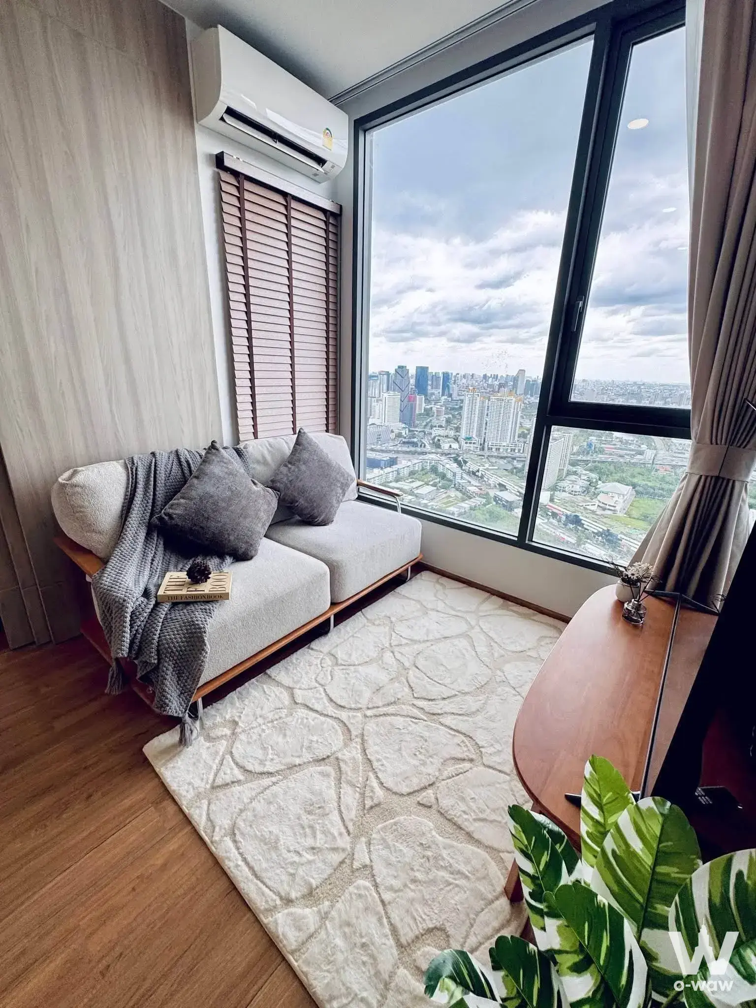 Living corner in a Cloud Thonglor-Phetchaburi condo with a grey sofa and panoramic city views