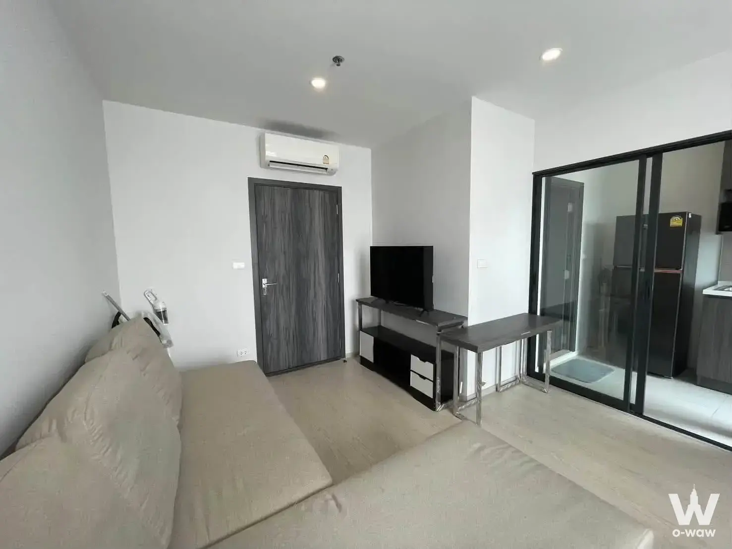 Modern living area in ELIO DEL NEST 1-bed condo featuring beige sectional and dark wood TV console