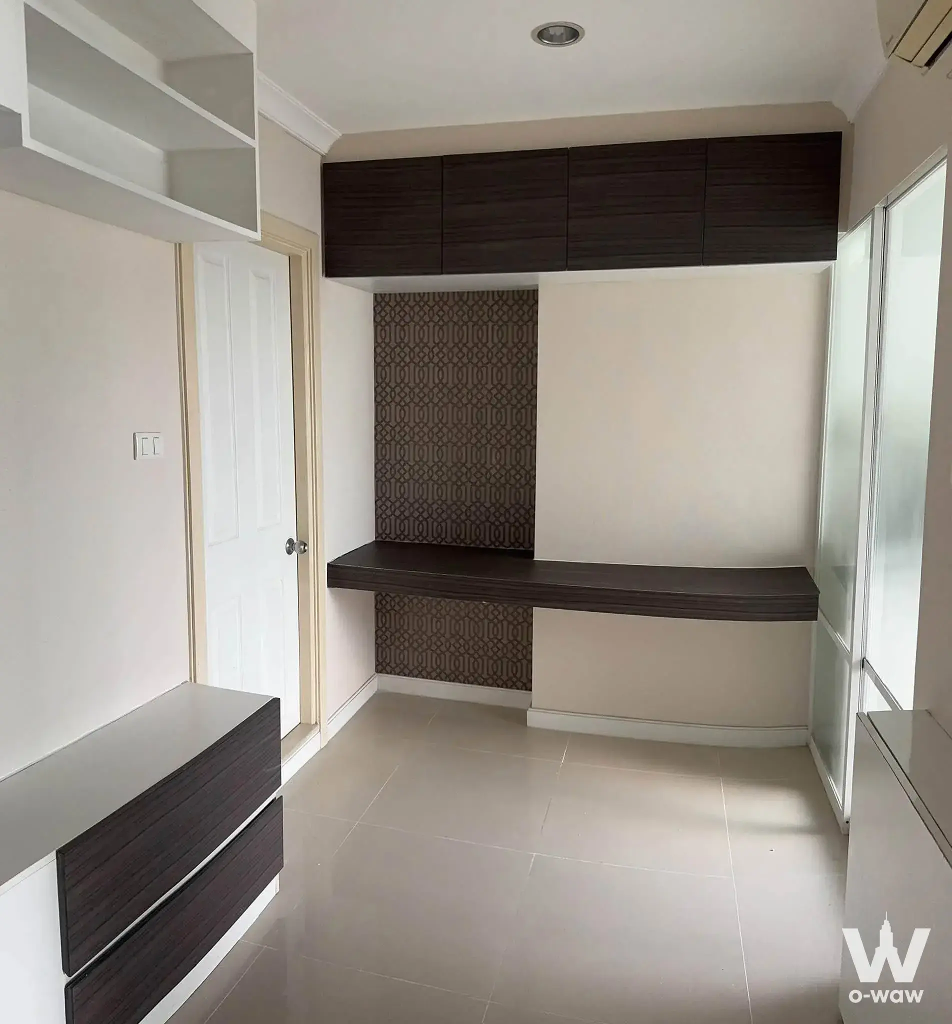 Built-in study nook with dark wood floating desk and geometric brown wallpaper in Lumpini Place Rama 8 condo