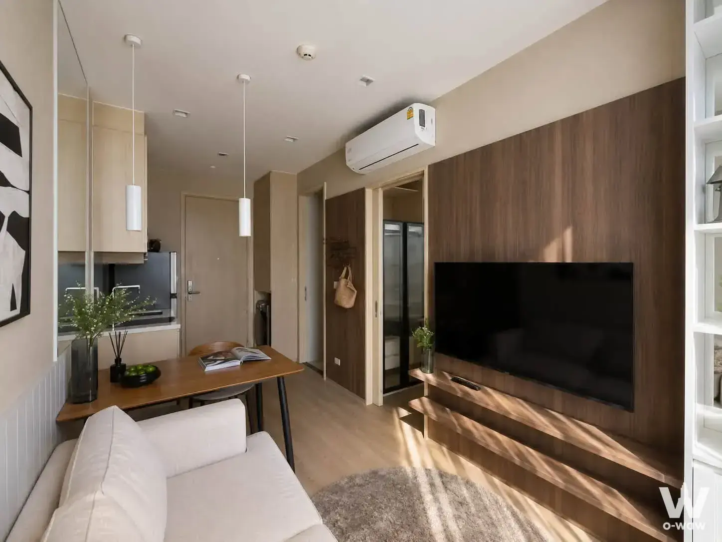 Furnished studio in Noble State 39 showing cream sofa, dining table, and walnut feature wall