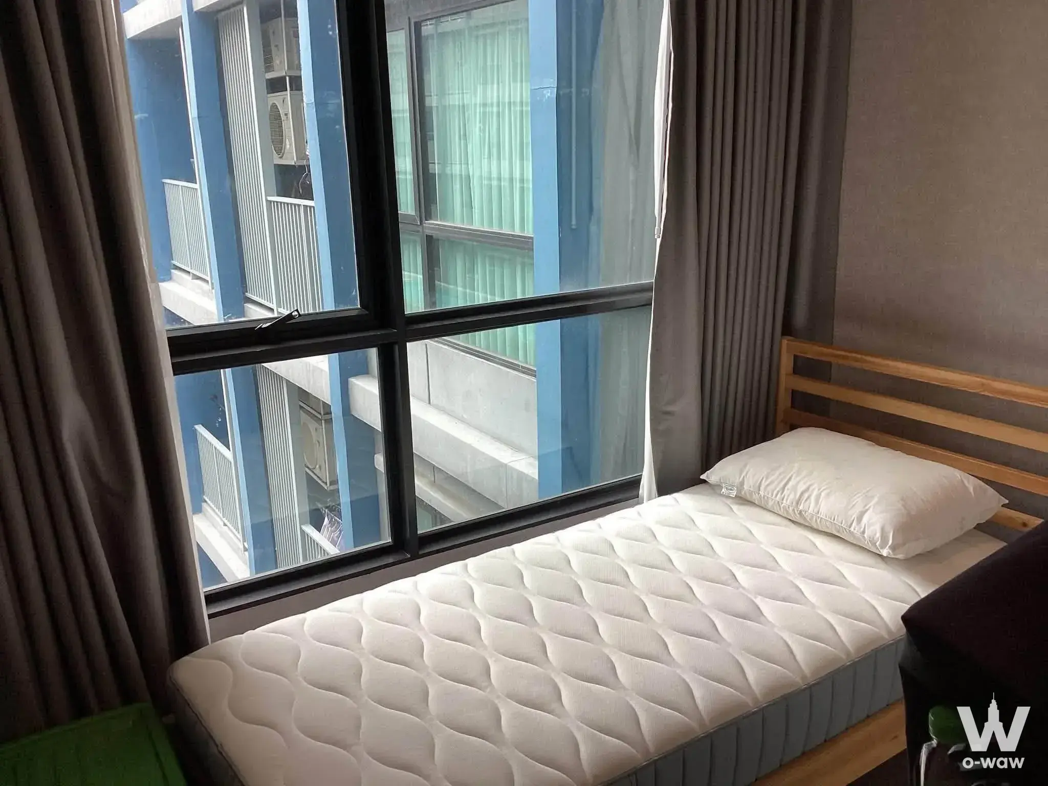 Bare bed with slatted headboard and floor-to-ceiling window in this 2-bed condo at The Origin Onnut