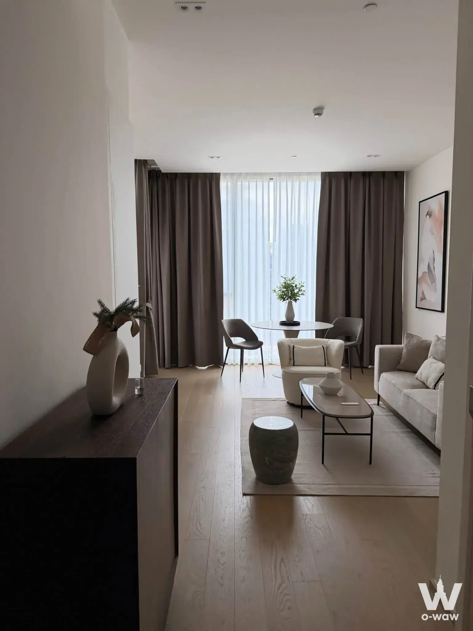 Living room in a 1-bed condo for rent in The Strand Thonglor with oak flooring, beige sofa, and dining nook
