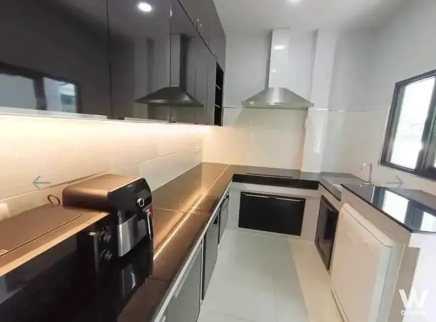 Modern galley kitchen with dark grey cabinets, black countertops, and stainless steel appliances