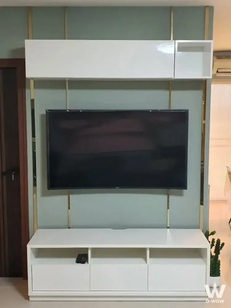 Modern living room with sage green accent wall and custom white gloss media unit in a 2-bed condo for rent in SV City Rama 3