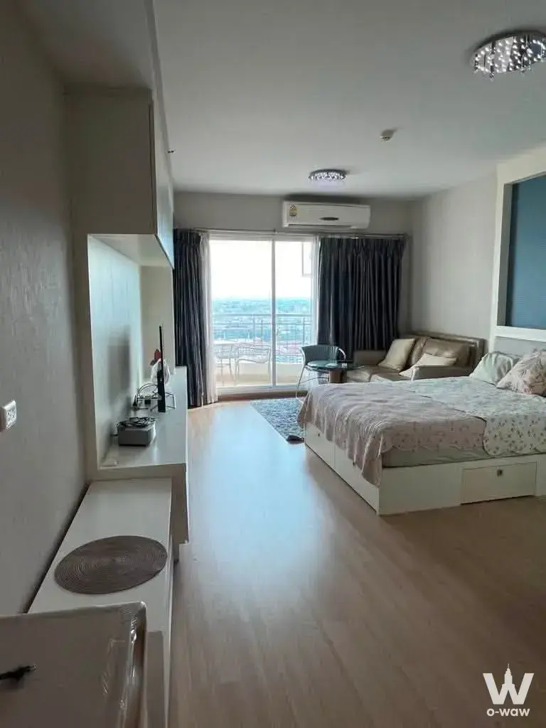 Open-plan studio in Supalai River Resort with queen bed, beige sofa, and balcony overlooking the city