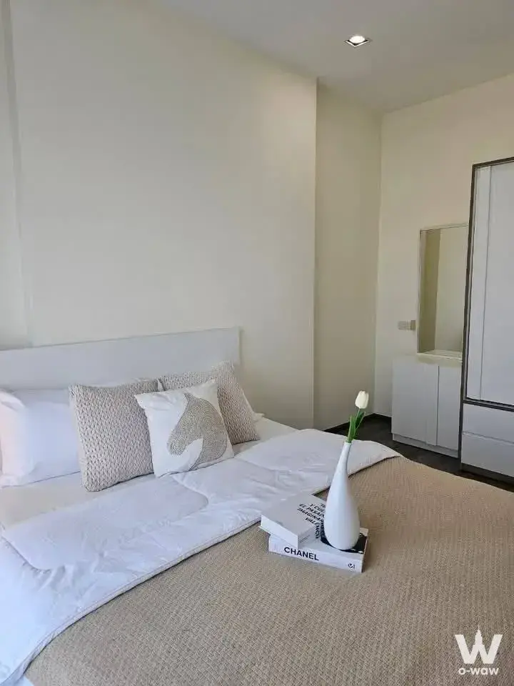 Staged bedroom in Rich Park Triple Station condo featuring Chanel books and white linens