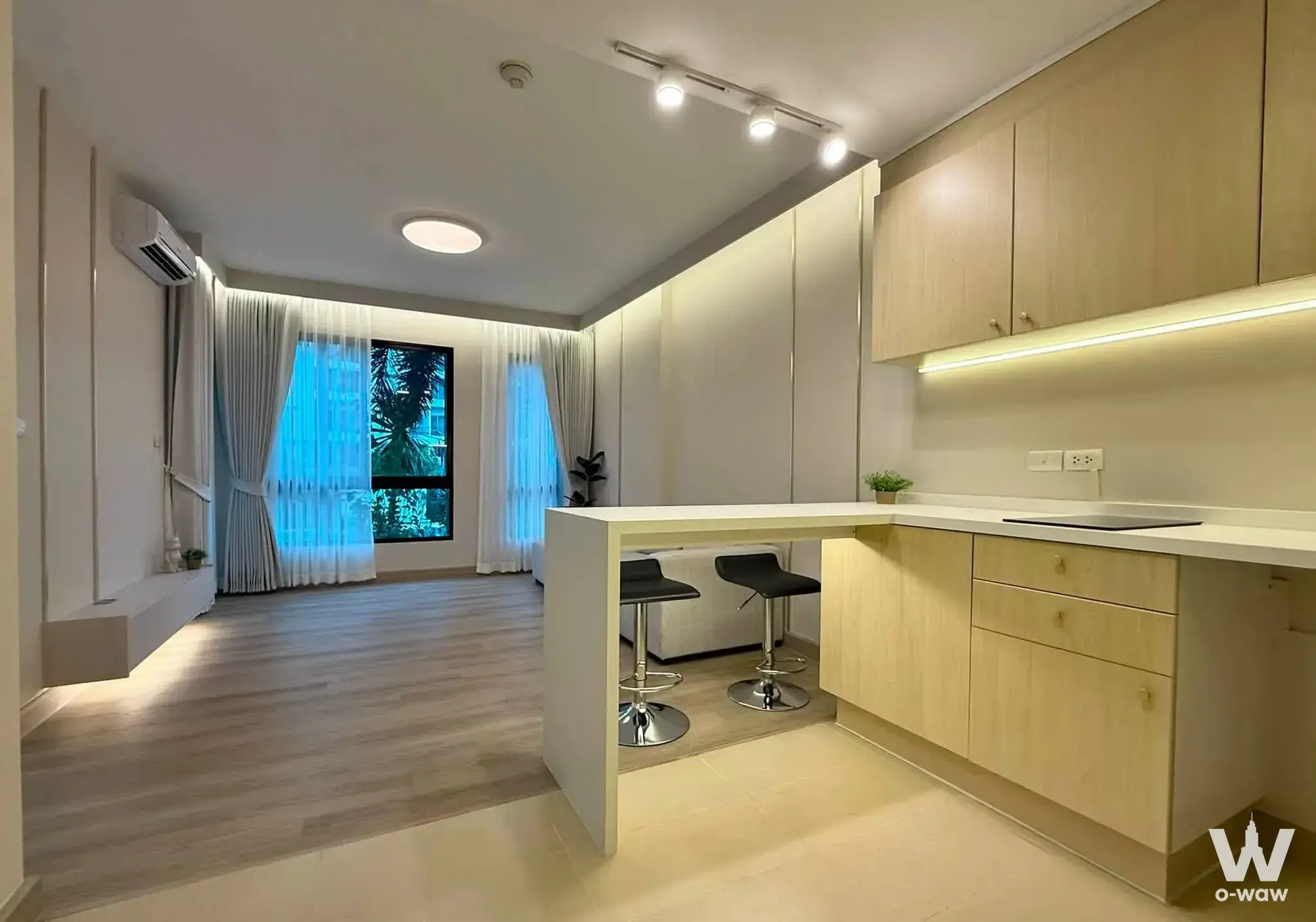Kitchen bar with stools and window view in a 1-bed condo for sale at The Sense Sukhumvit
