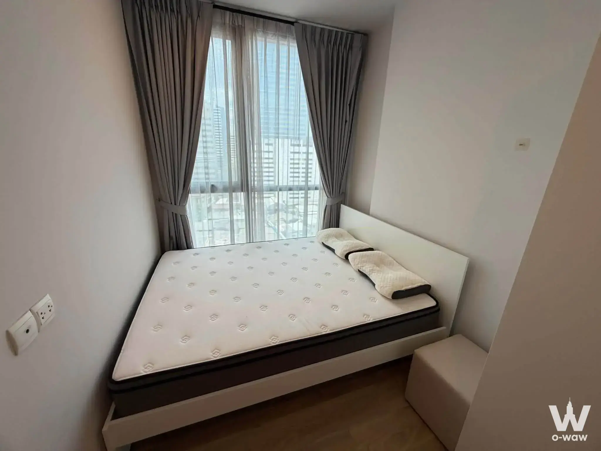 Bedroom in a 2-bed condo for rent at Oka Haus with a queen bed, light oak flooring, and city skyline views