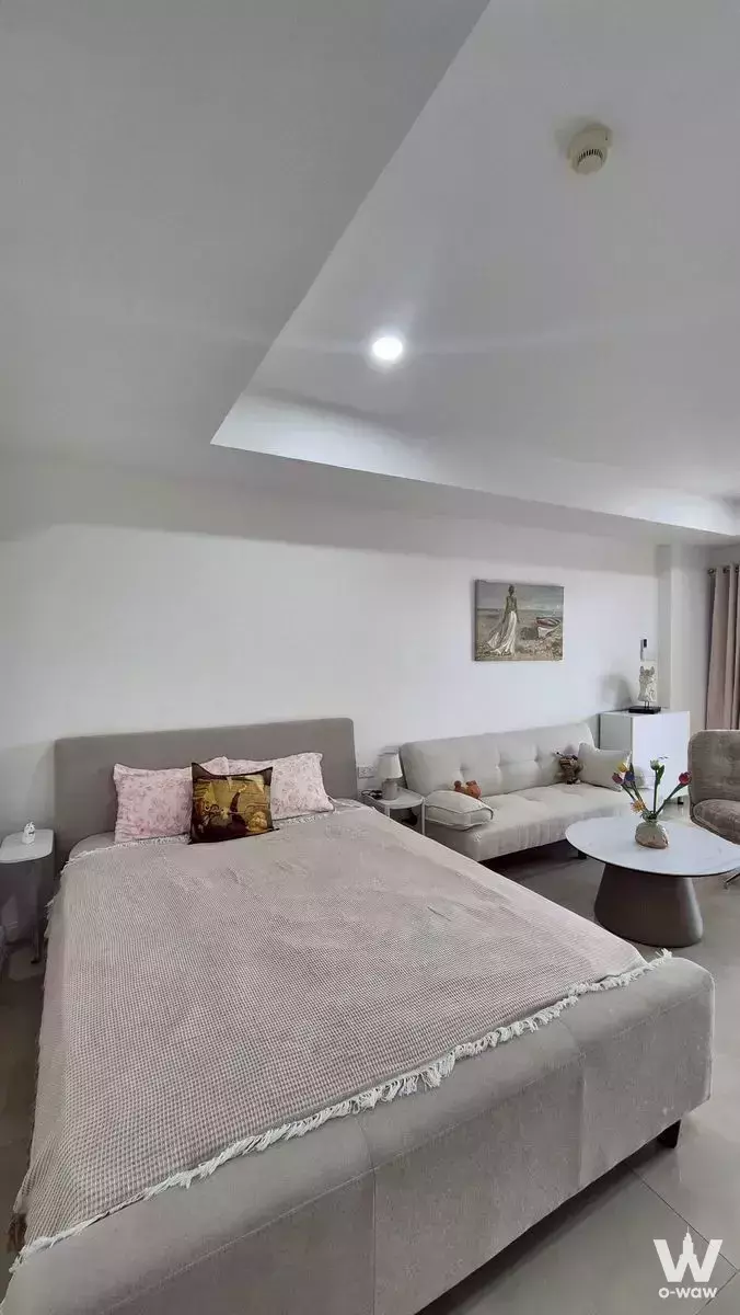 Grey bed with pink throw in Nova Mirage 1-bed condo