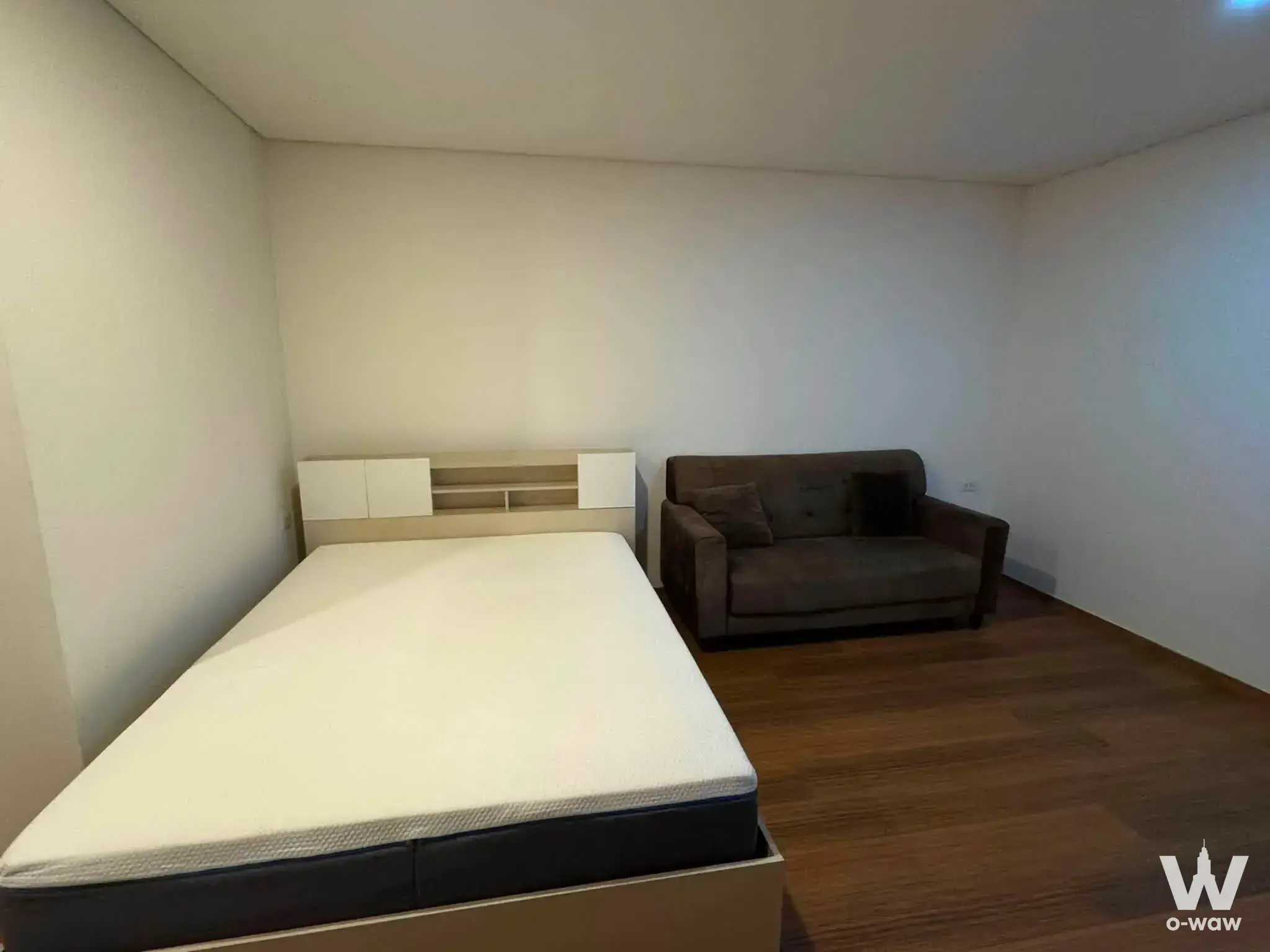 Compact bedroom in a Lumpini Condotown Ekachai 48 rental featuring a queen bed and brown sofa