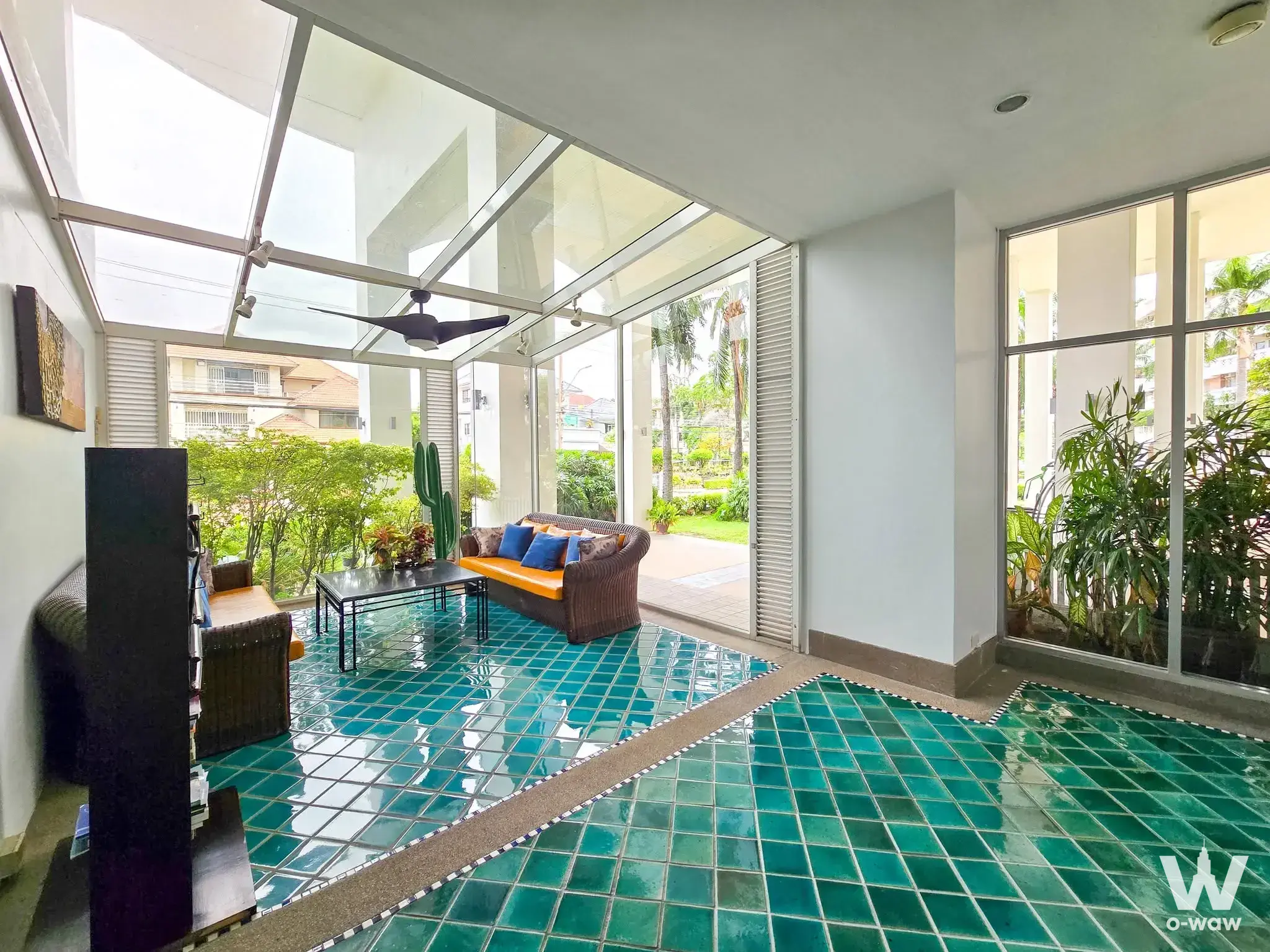 2-bed condo for rent in Thara Ruean Kaew featuring a sunroom with teal tile floor and wicker sofa