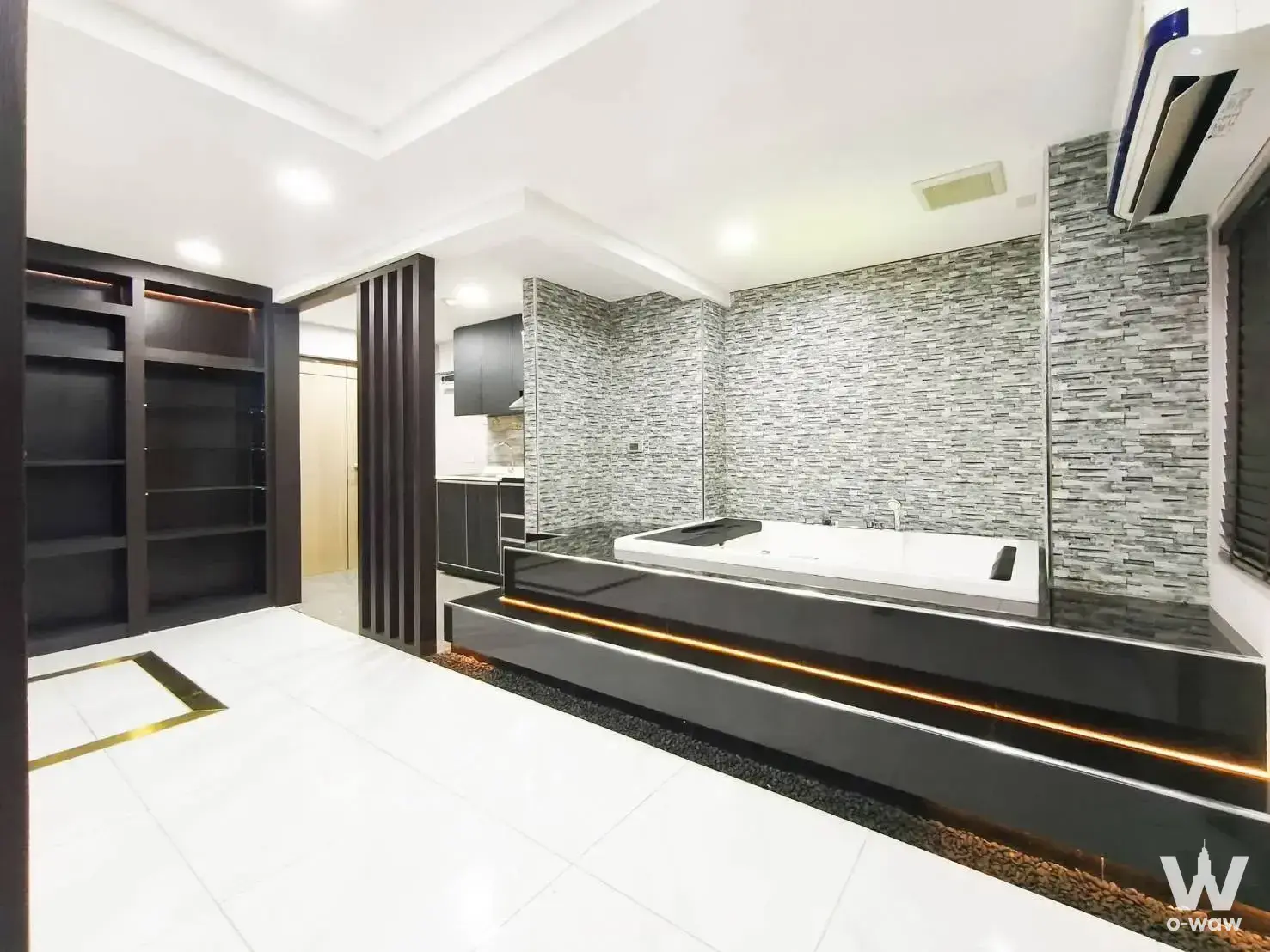 Luxury master bathroom with black platform tub and grey stone wall in The Kris 3 condo