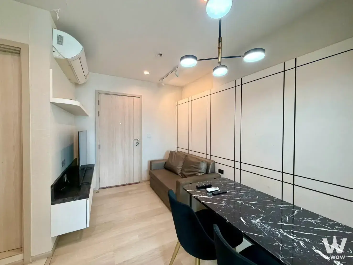Living room in Life One Wireless condo with brown leather sofa and black marble dining table
