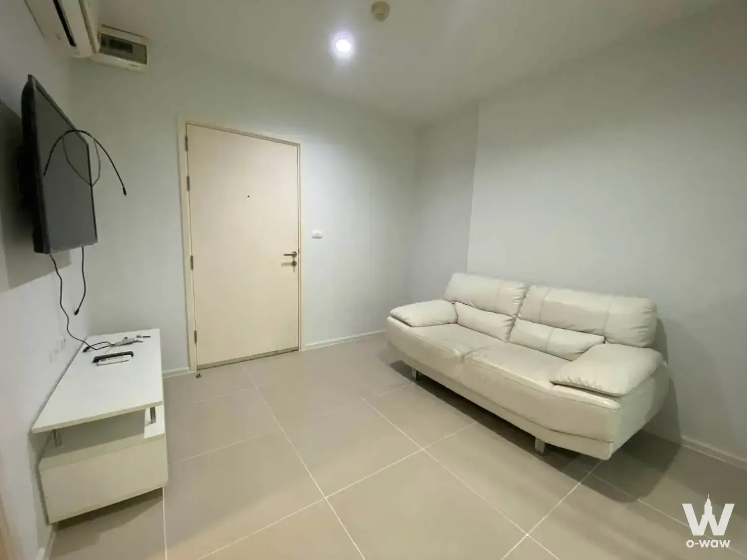 Minimalist living room in an Aspire Rama 9 one-bed condo with off-white leather sofa and wall-mounted TV