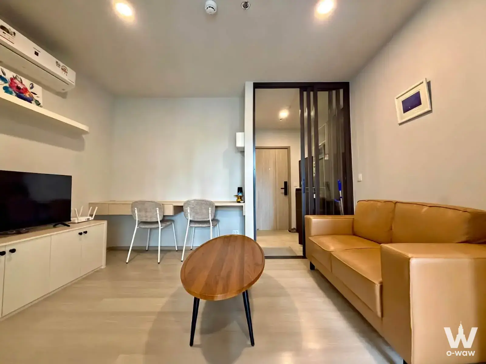Aspire Onnut Station 1-bed condo living room featuring tan sofa, media cabinet, and desk area