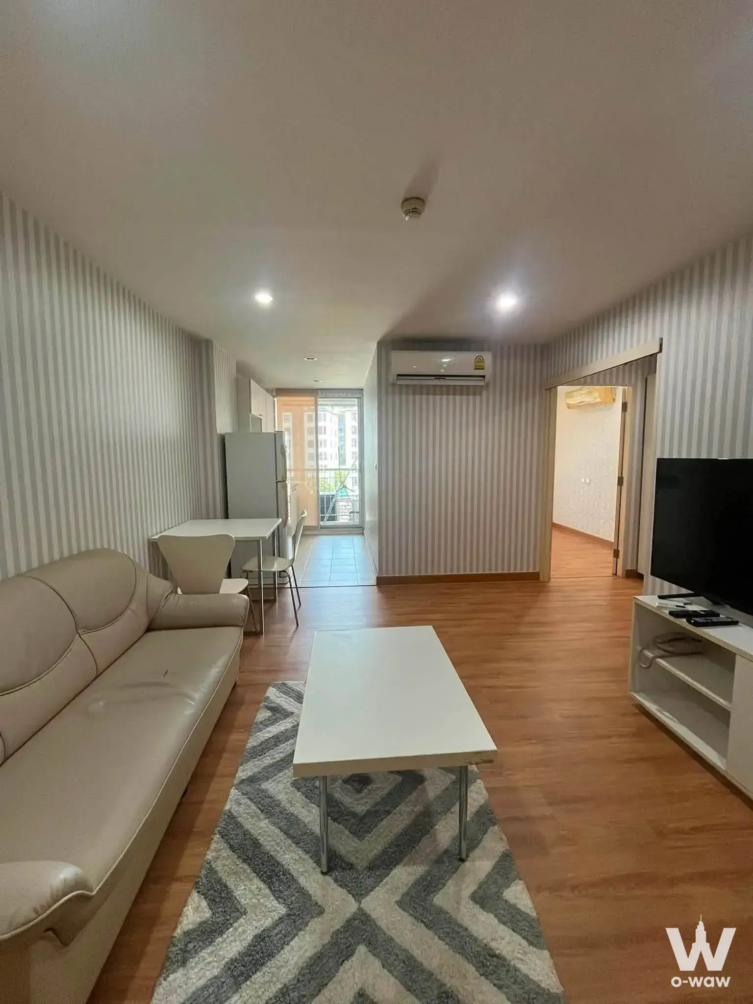 Living room in The Niche Sukhumvit 49 condo with beige leather sofa and chevron rug