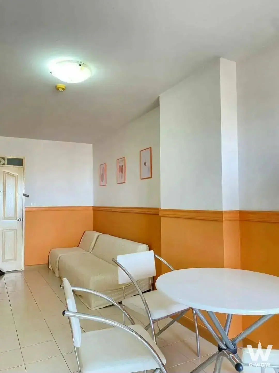 Living room with orange wainscoting and chrome dining set in City Home Sukhumvit 1-bed house