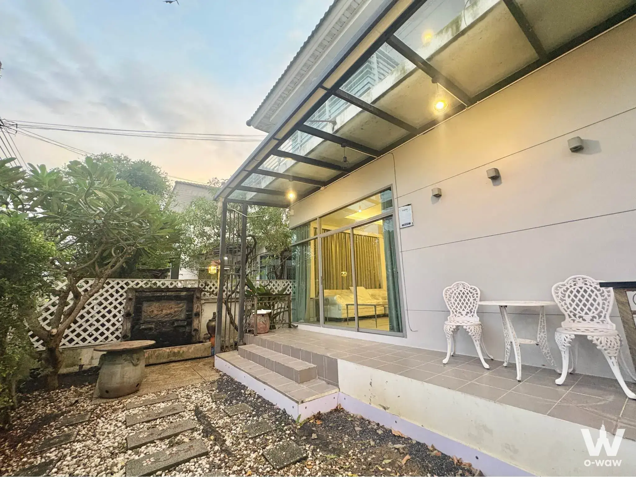 Garden patio with bistro set and open sliding door leading into the living room of a 3-bed condo
