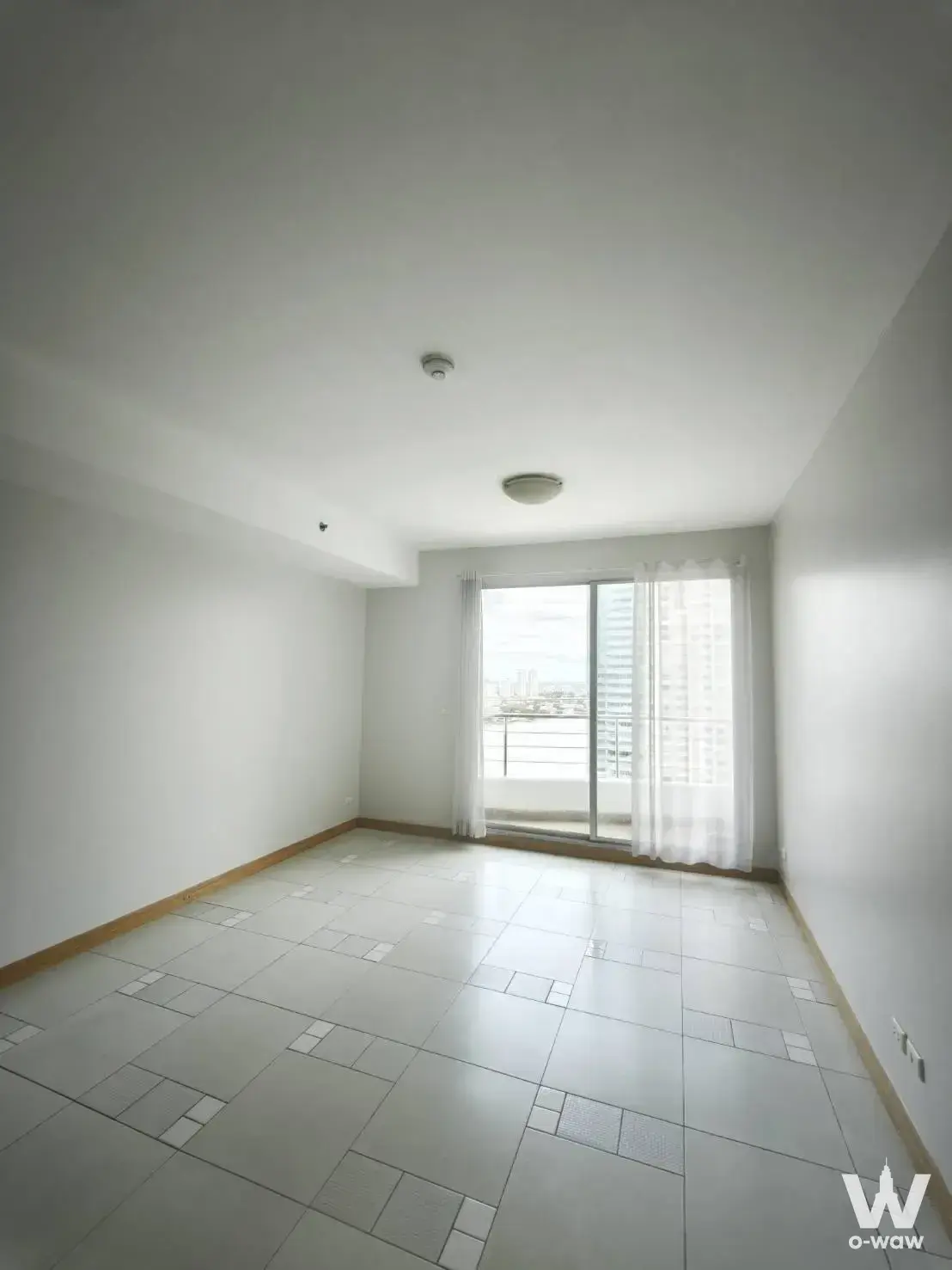 Empty living room in Supalai River Place with grey tile floors and sliding glass balcony doors