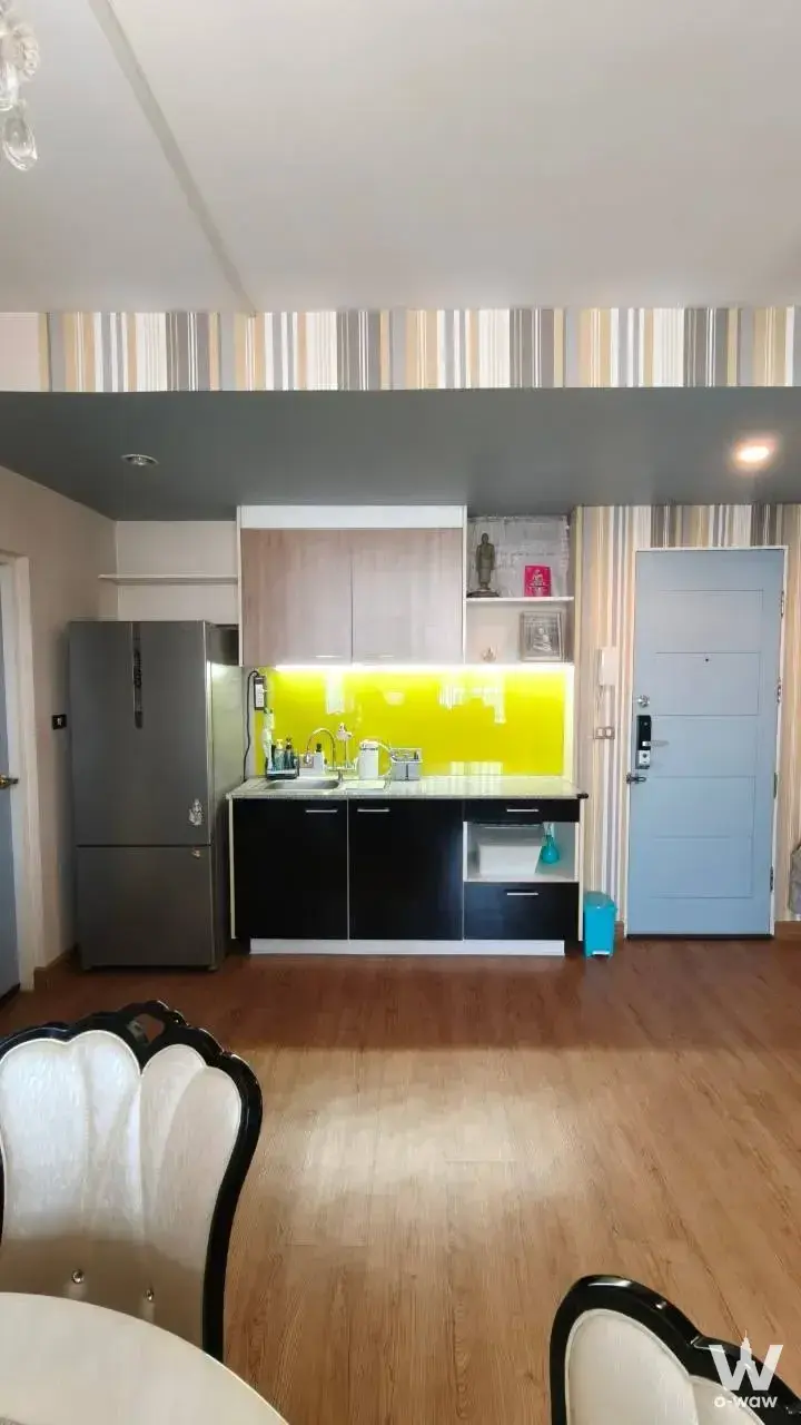 Kitchen with lime-green backsplash and dining chairs in 1-bed condo for sale at The Iris Condo
