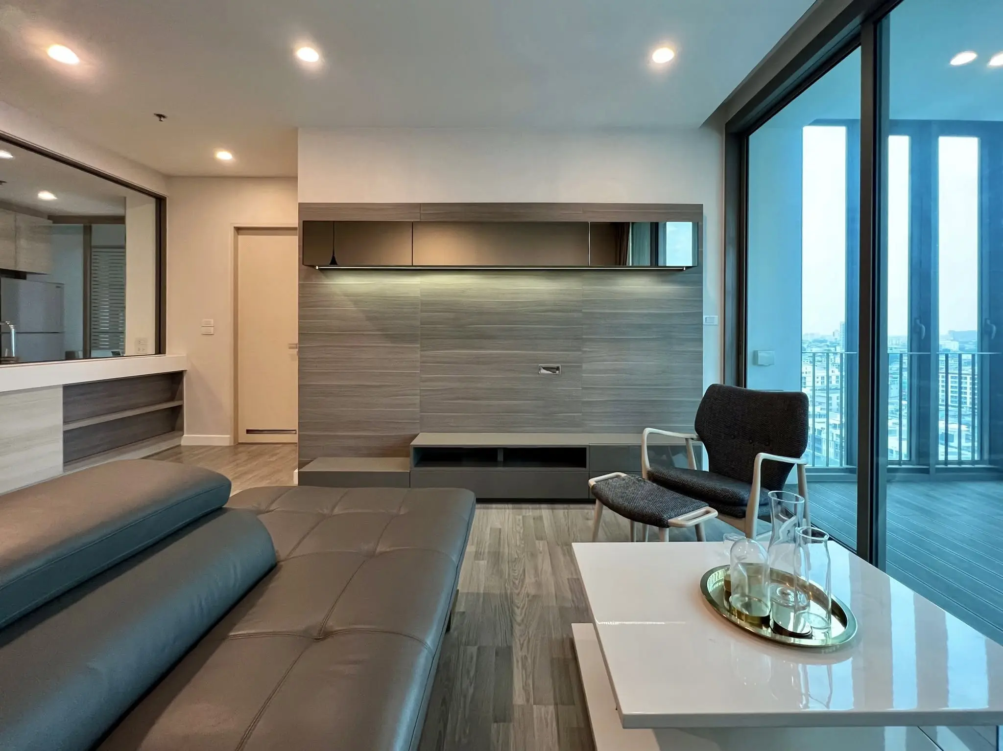2-bed condo for rent in The Room Wongwian Yai featuring dark-grey sectional and city skyline view