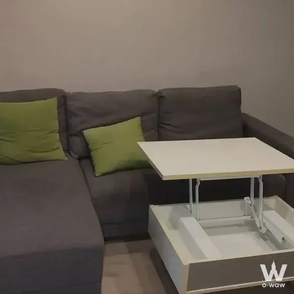 Living room in a 1-bed Sathon condo with a grey sectional and lime-green pillows on light wood floors