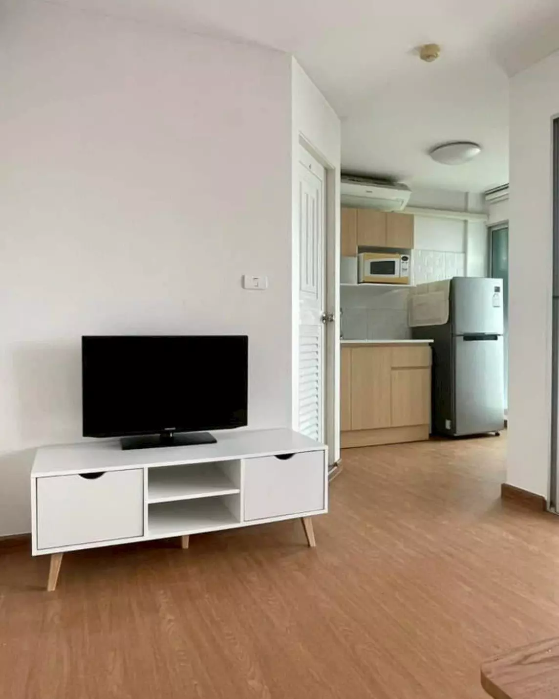 Open-plan living area in Dcondo Rattanathibet 1-bed condo for sale with light wood floors and compact kitchen