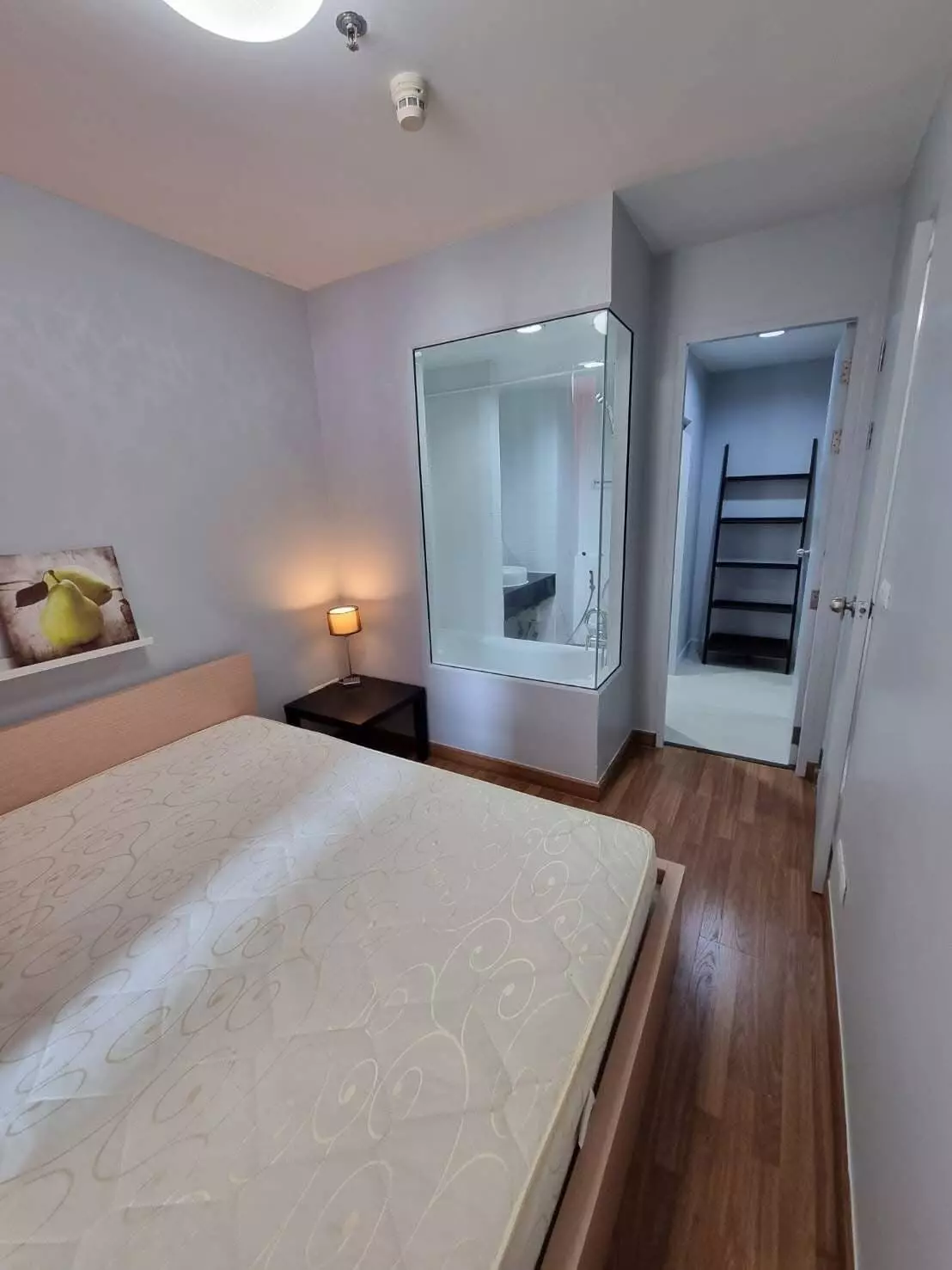 Modern bedroom with wood floors, beige bed, and glass bathroom partition in Ideo Mix Sukhumvit 103 condo