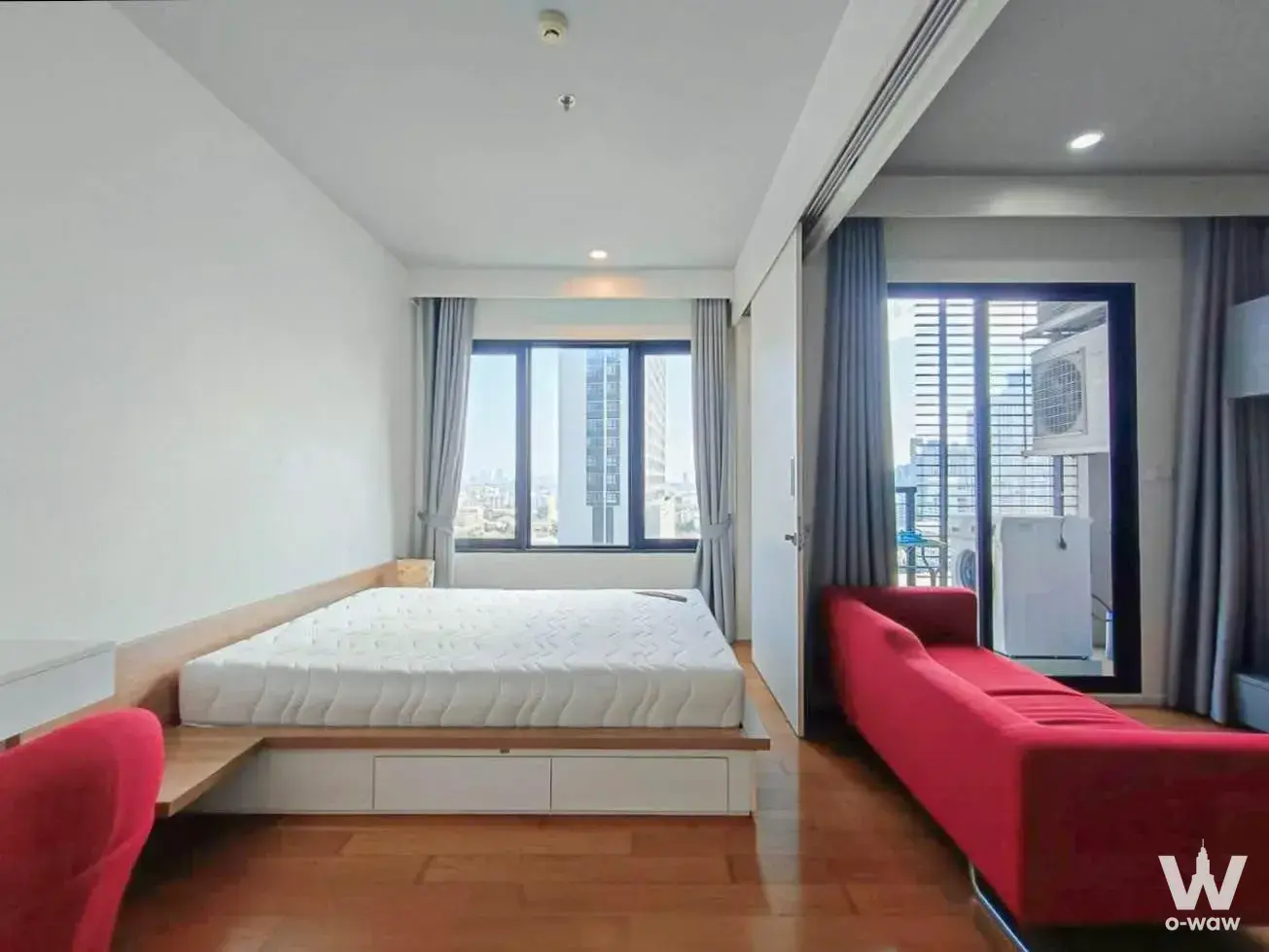 Bedroom in Blocs 77 1-bed condo featuring red armchair and queen bed with storage base