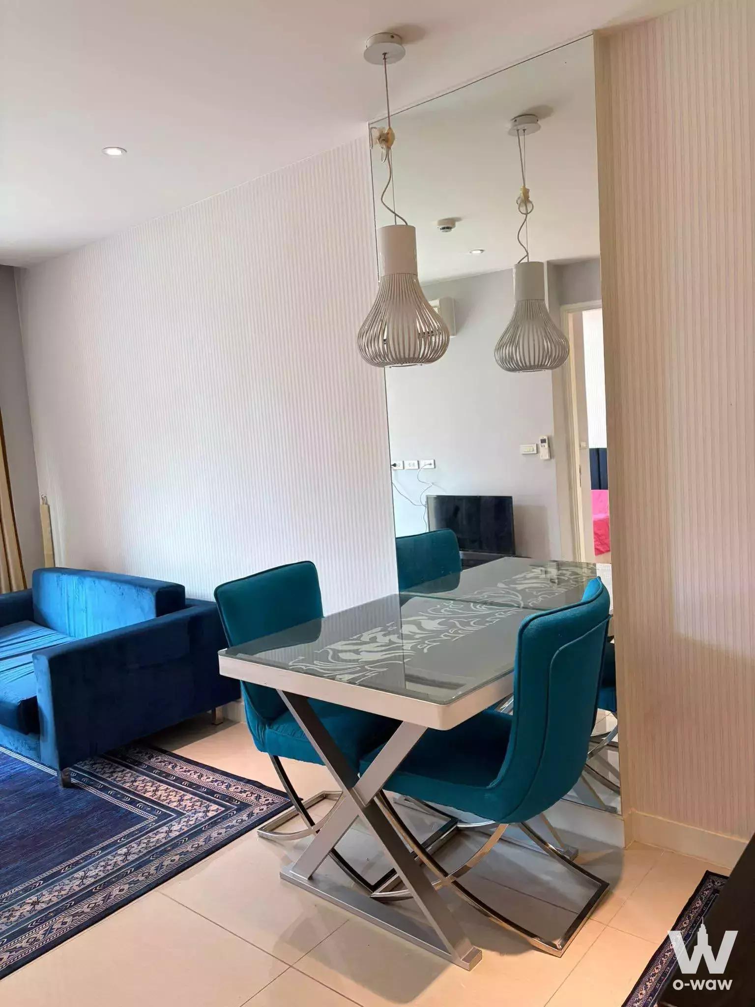 Dining area in Grande Caribbean Condo featuring glass table, teal velvet chairs, and fluted wall paneling