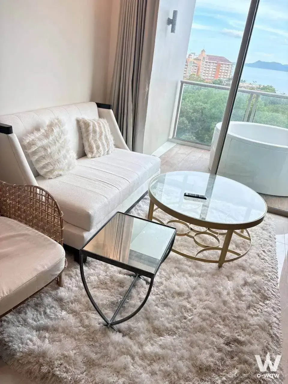 Living area in Riviera Monaco condo with grey rug, white sofa, and balcony access to outdoor soaking tub