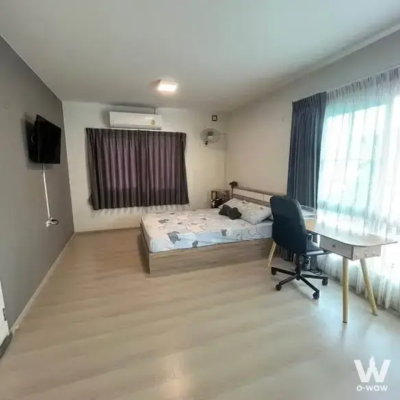 Bedroom in a 3-bed townhouse for rent in Villaggio Bangna with a dark grey accent wall and white desk by the window