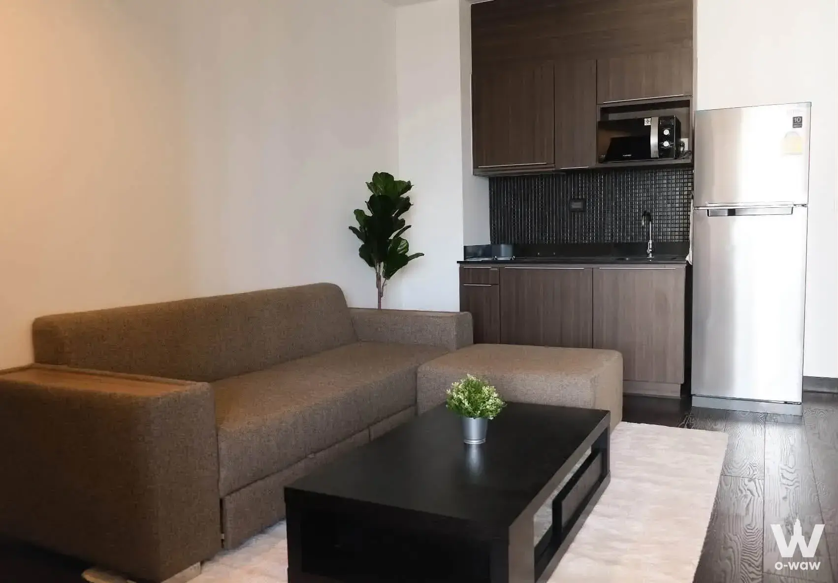 L-shaped brown sofa and compact kitchenette in Ideo Q Phaya Thai studio apartment