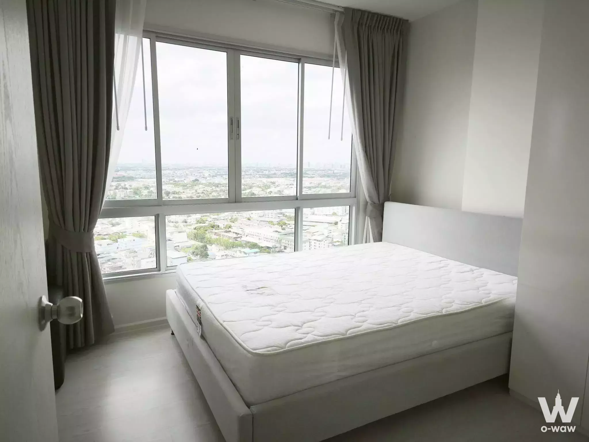 Spacious bedroom in The Prodigy Condo with glossy tile floors, bare mattress, and panoramic city views