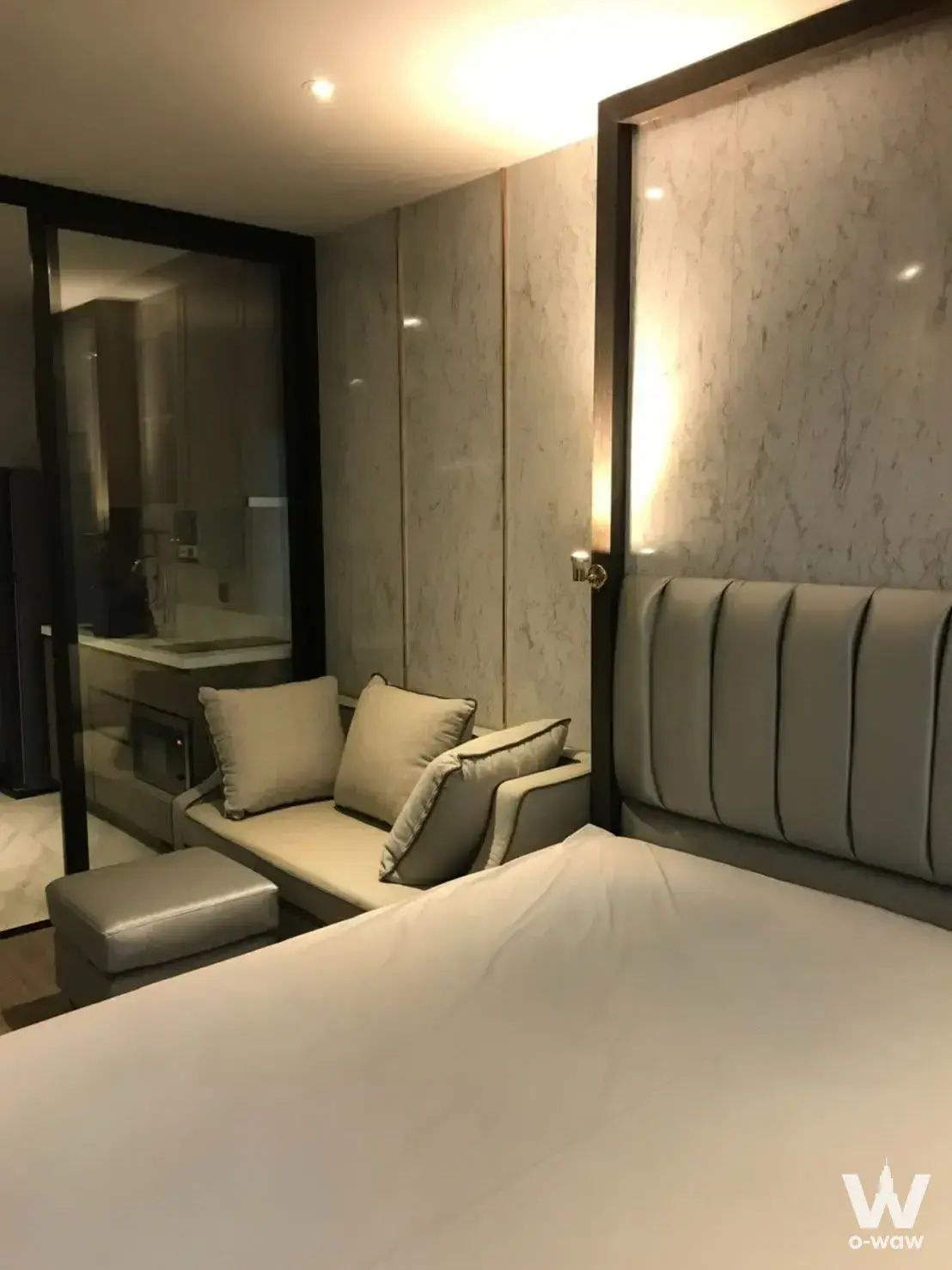 Rhythm Ekkamai 1-bed condo rental master bedroom with marble wall, tufted headboard, and wet bar