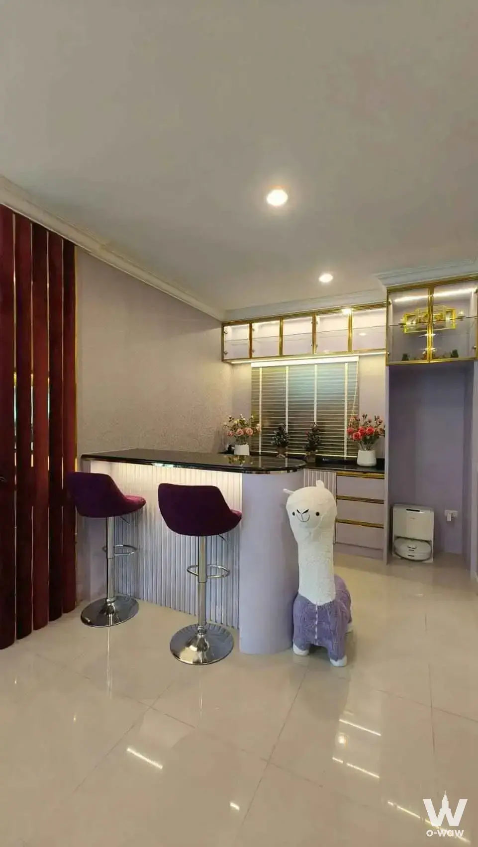 Eclectic condo bar area featuring a purple velvet stool, llama toy, and gold-trimmed cabinetry