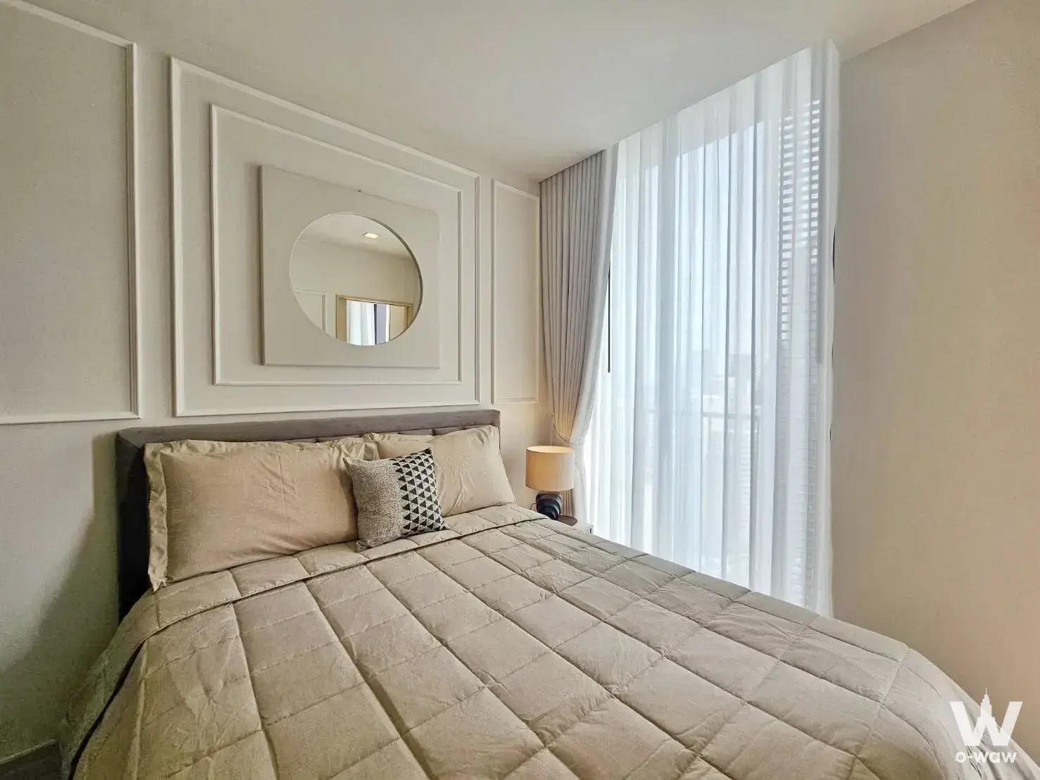 Minimalist bedroom with dark grey headboard, circular mirror, and sheer curtains in Noble State 39