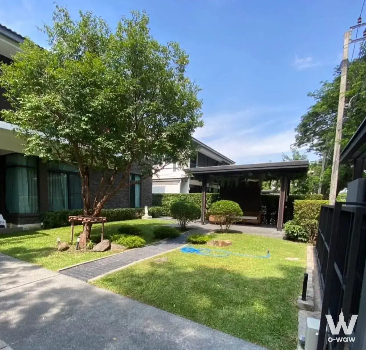 Modern house exterior with manicured lawn and wooden carport at this 4-bed rental property in Mantana Bangna Km.15