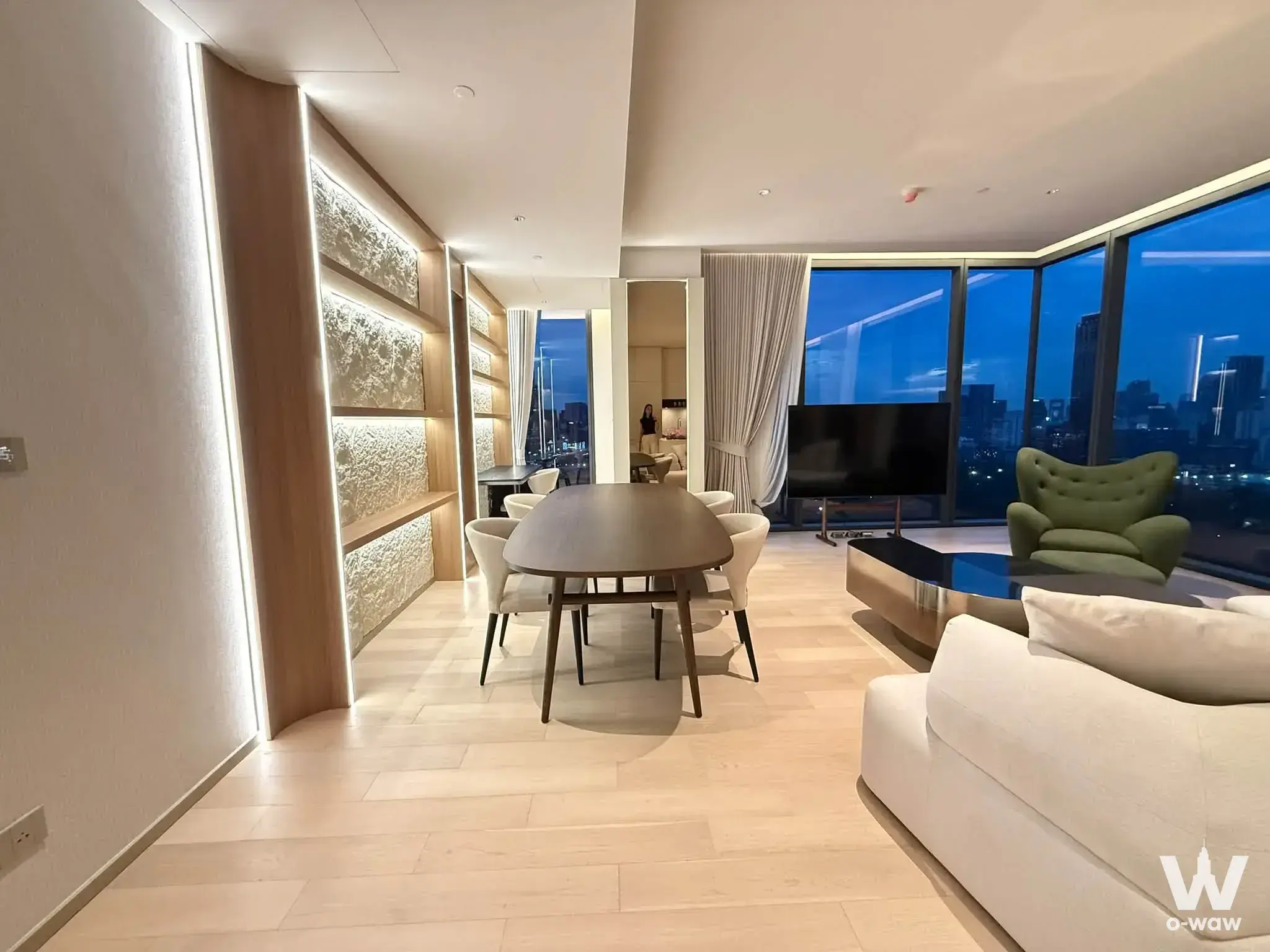 Open-plan living area with LED-lit shelving and panoramic night views in a luxury condo for rent at EI8HTEEN SEVEN