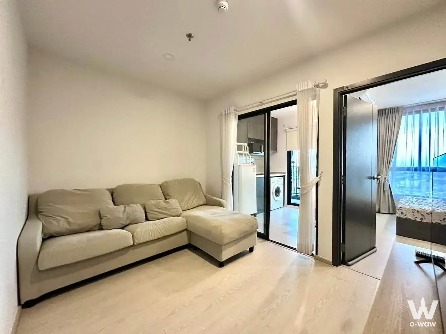 Living room with beige sectional sofa and sliding glass doors to kitchen in a 1-bed condo for rent at Elio Del Nest