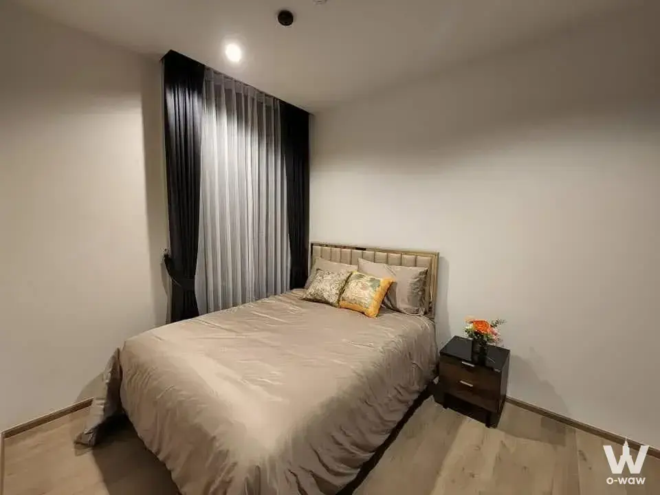 Queen bed with gold headboard in a minimalist 1-bed condo at Quinn Sukhumvit