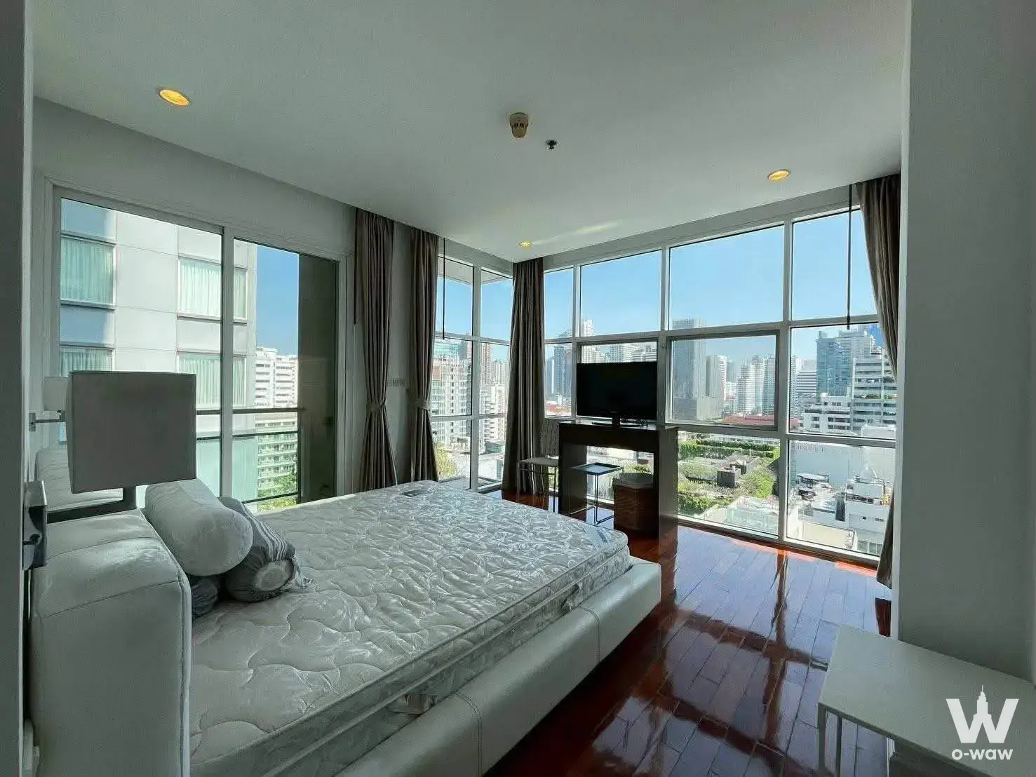 2-bed PRIME MANSION 1 bedroom with dark hardwood floors, white bed frame, and expansive city skyline view