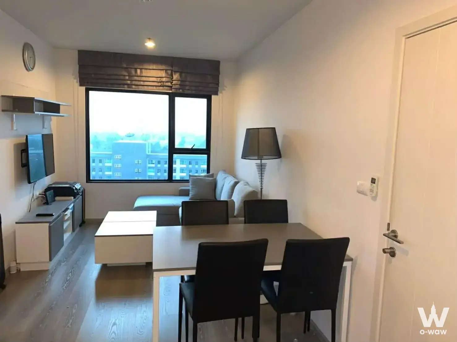 Open-plan living area with grey sectional sofa and dining set in 2-bed condo for sale in Aspire Sathorn-Taksin Copper Zone