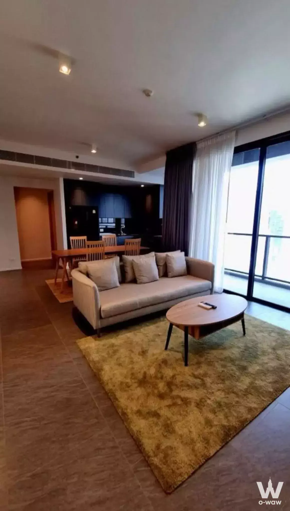 Spacious living room with mustard rug and balcony view in this 2-bed land for sale at The Lofts Silom
