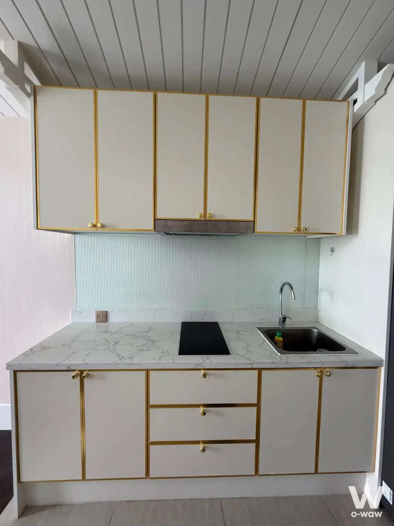 Compact kitchen in a 1-bed condo for rent in Grand Florida Pattaya with cream cabinetry and blue tile backsplash