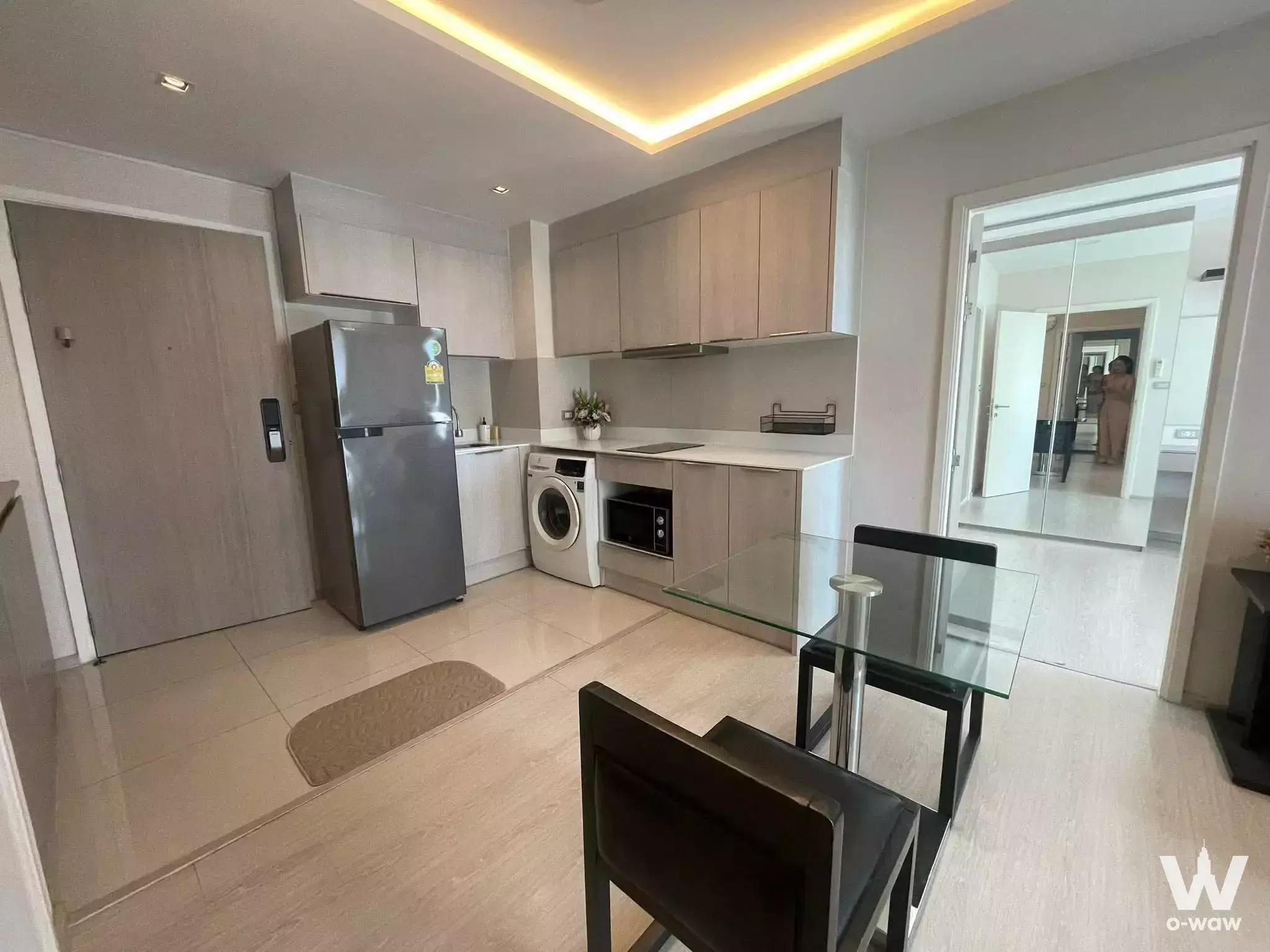 Open-plan kitchen in VTARA Sukhumvit 36 with light oak cabinets, white countertops, and dining set