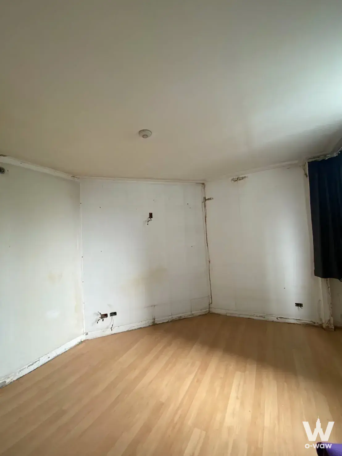 Empty vacant room with scuffed walls and laminate flooring for sale in Supalai Park