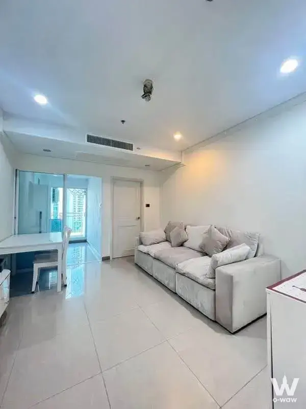 Supalai Wellington II 1-bed rental living room with light-grey sofa, glossy white tile floors, and natural daylight