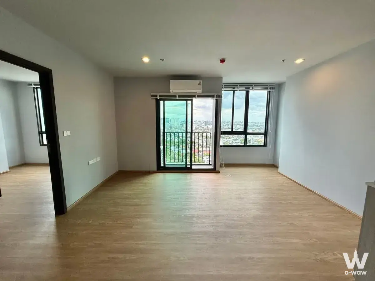 Unfurnished living room in Nue Evo Ari condo with laminate floors and sliding glass door to balcony