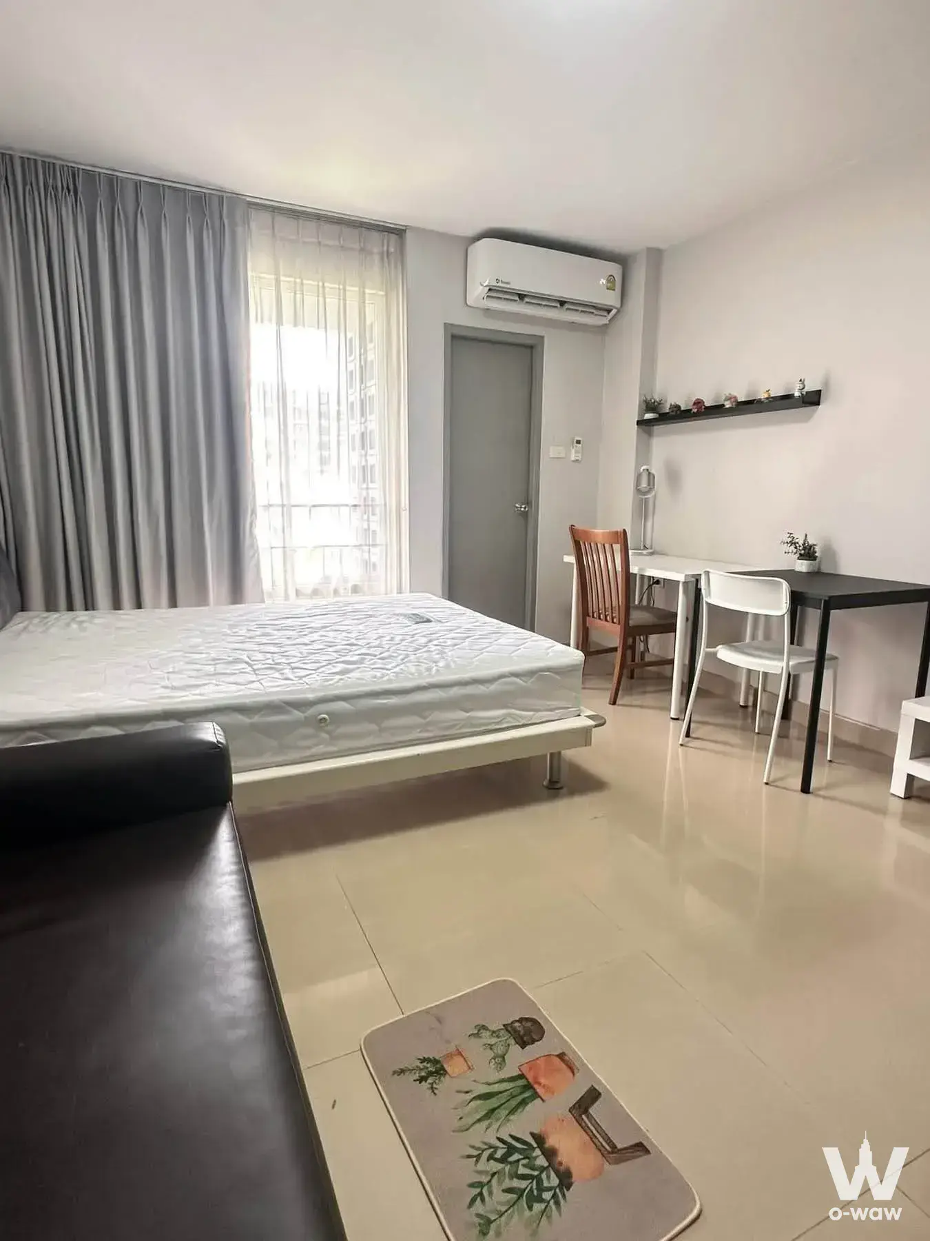 Studio bedroom in i-House Laguna Garden RCA with queen bed, desk, and high-rise city view through sheer curtains